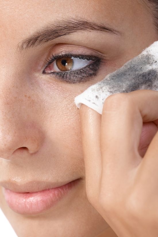 Closeup portrait of young woman removing eye makeup, by cotton pad.